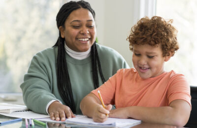 A teacher's assistant helps a young student with his schoolwork.