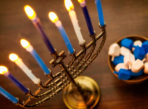 Photograph of a lit menorah and bowl of dreidels