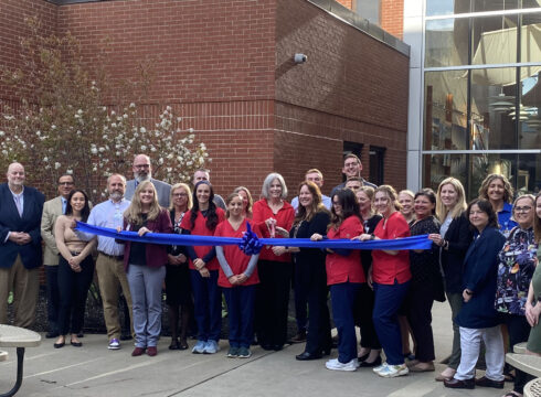 New England College President Wayne Lesperance, far left, joins nursing students and Portsmouth Regional Hospital staff at the ribbon-cutting celebrating the hospital’s cohort of 20 NEC nursing students who begin their clinical experiences in May.