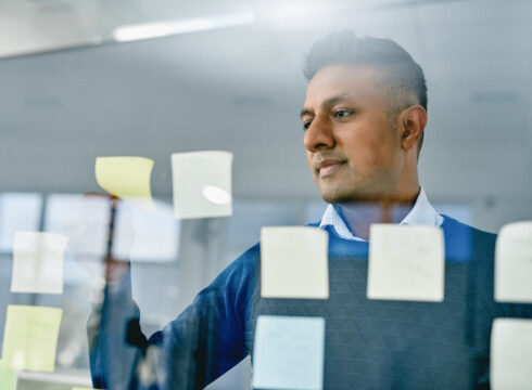 Male information technology project management professional looks at projects on a board.