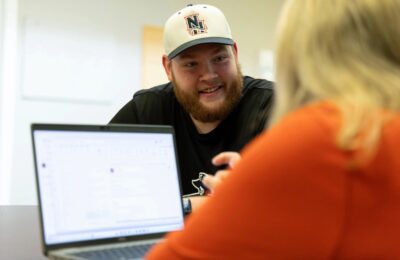 Student at New England College sits with a mentor as part of the College's add-on Mentoring program.