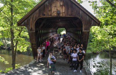 Students crossing the covered bridge during Convocation 2024 at New England College