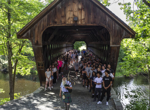 Students crossing the covered bridge during Convocation 2024 at New England College