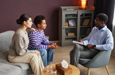 A counselor talks to a parent and child in an office