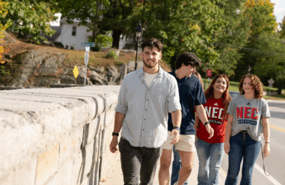 Students at New England College walk across the stone bridge in Henniker, NH.