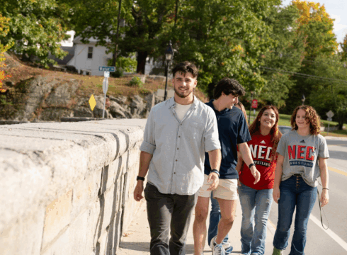 Students at New England College walk across the stone bridge in Henniker, NH.