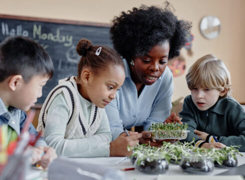 A teacher works with students studying photosynthesis