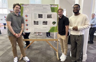 Students stand with their poster presentation during the New England College Student Showcase 2025.