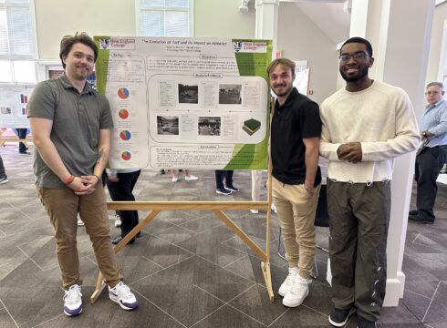 Students stand with their poster presentation during the New England College Student Showcase 2025.