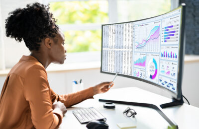 A data scientist uses a monitor displaying a visualization dashboard to analyze data.
