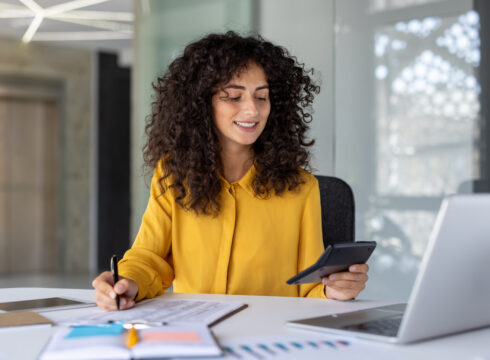 A CPA uses a calculator and a laptop to analyze financial data.