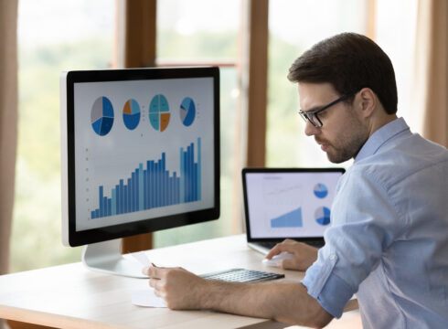 An accountant prepares a financial report using data visualization software on a monitor.