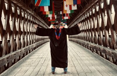 New England College alumnus one the College's covered bridge on Commencement Day 2026