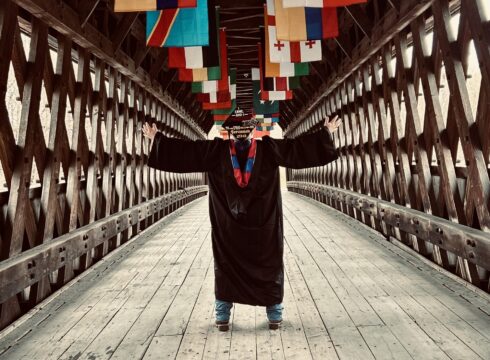New England College alumnus one the College's covered bridge on Commencement Day 2026