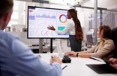 An accountant presents financial data on a video screen in a conference room.