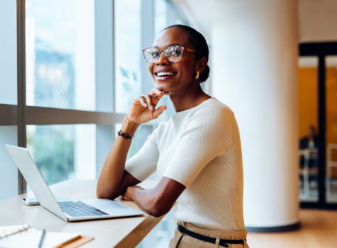 A smiling executive seated at a desk in an office.