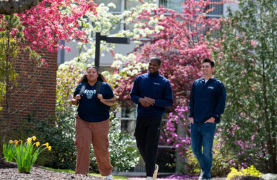 Three students walk across the campus of New England College in Henniker, NH.