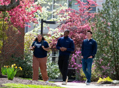 Three students walk across the campus of New England College in Henniker, NH.