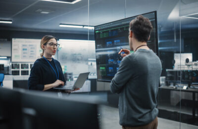 AI engineers working together with a laptop near a board.