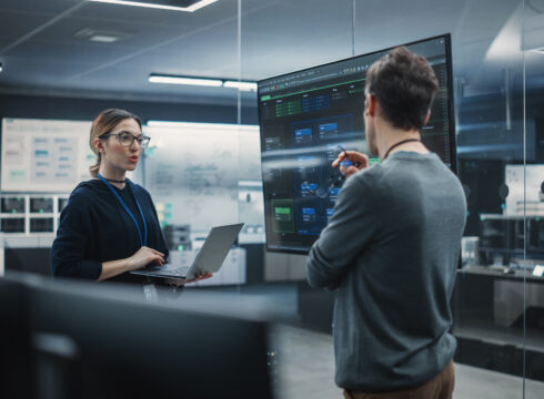 AI engineers working together with a laptop near a board.