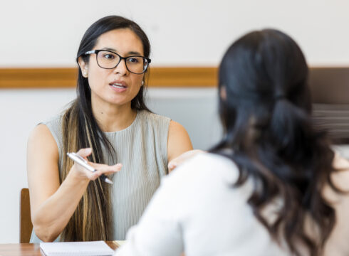 A counselor talking to a client at a desk.