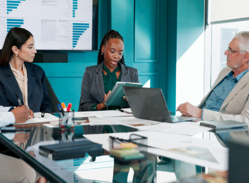 Executives meet around a conference table.
