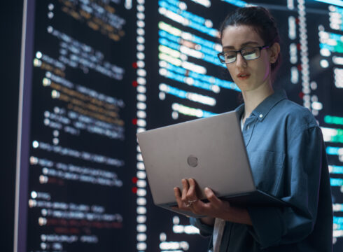 A cybersecurity professional analyzes code on a laptop.