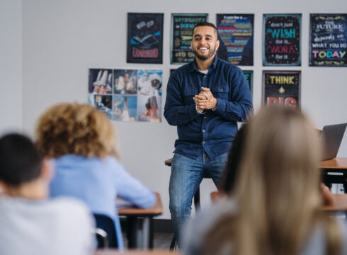 A teacher stands at the front of a classroom.