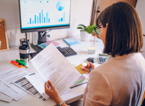 A budget analyst prepares a report using documents and data visualization software.